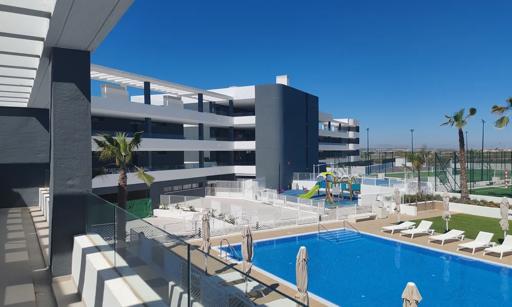 Inicio 14 IUrbanización moderna con apartamentos, piscina comunitaria y zonas de ocio.